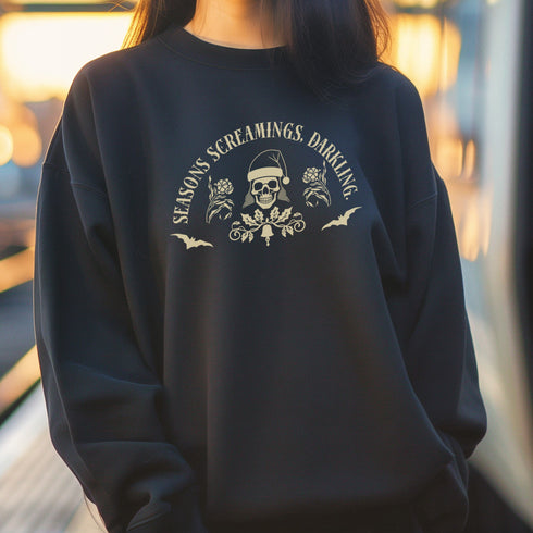 Christmas sweatshirt with "SEASONS SCREAMINGS, DARKLING" text arched over a skull wearing Santa hat. Bats, flowers, and ornate designs surround the skull in vintage-inspired style.